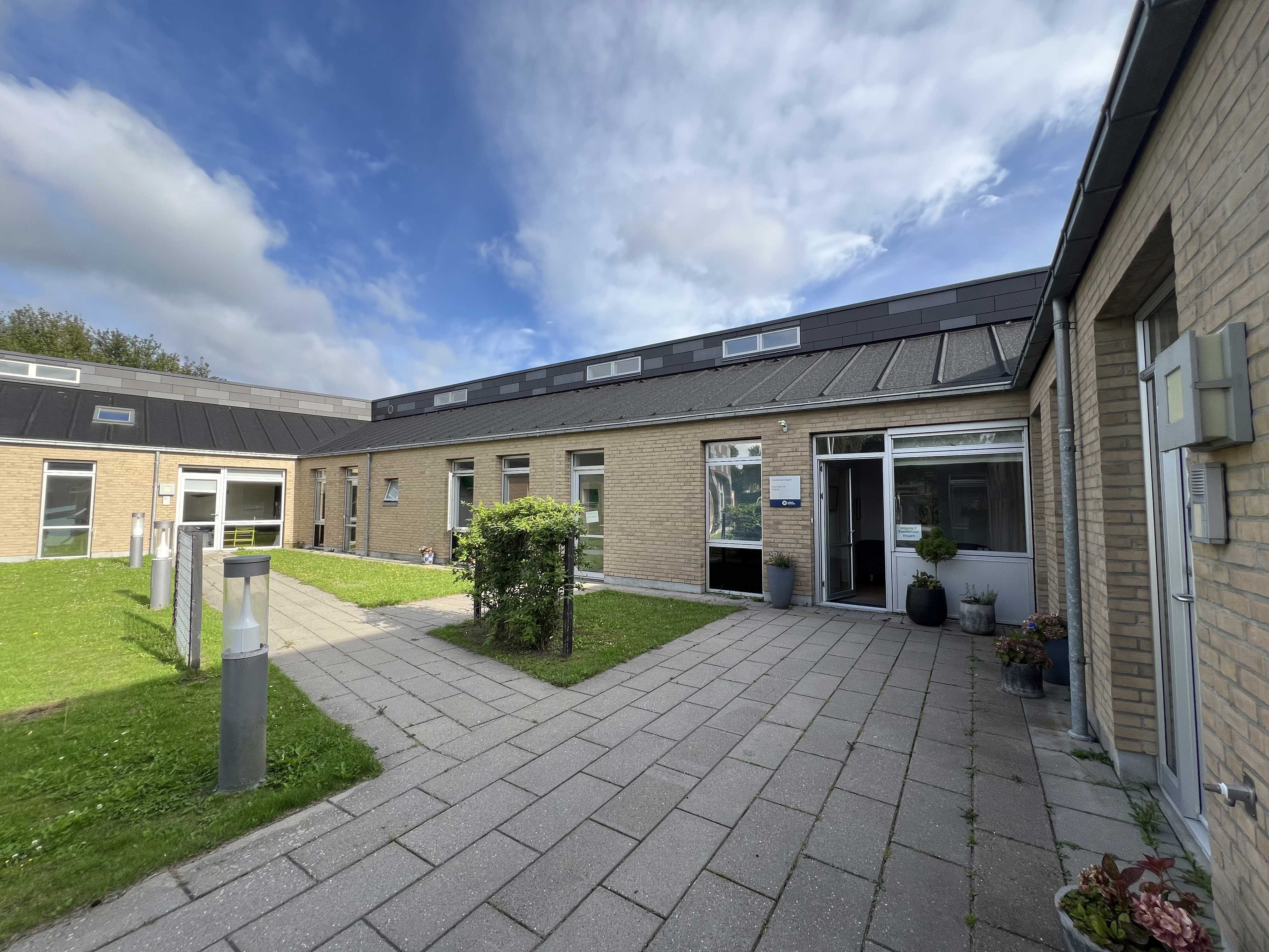 Familiehuset Bisgård Udefra med græsplæne og terrasse