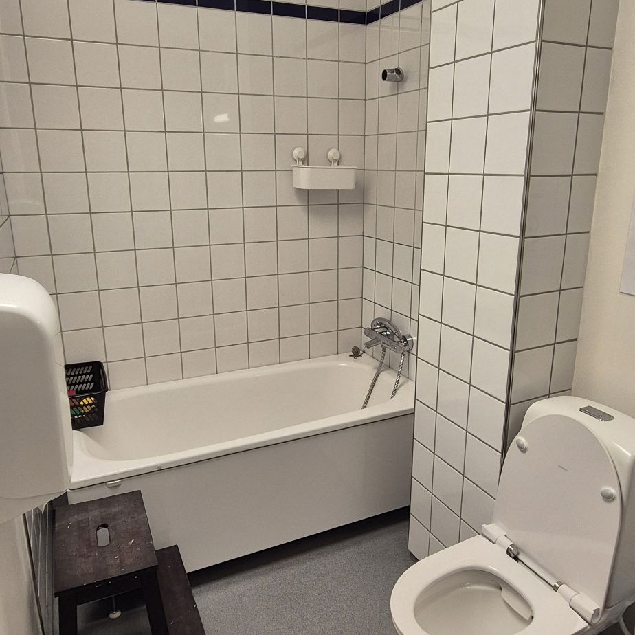 Badeværelse ned hvide fliser, toilet og badekar
