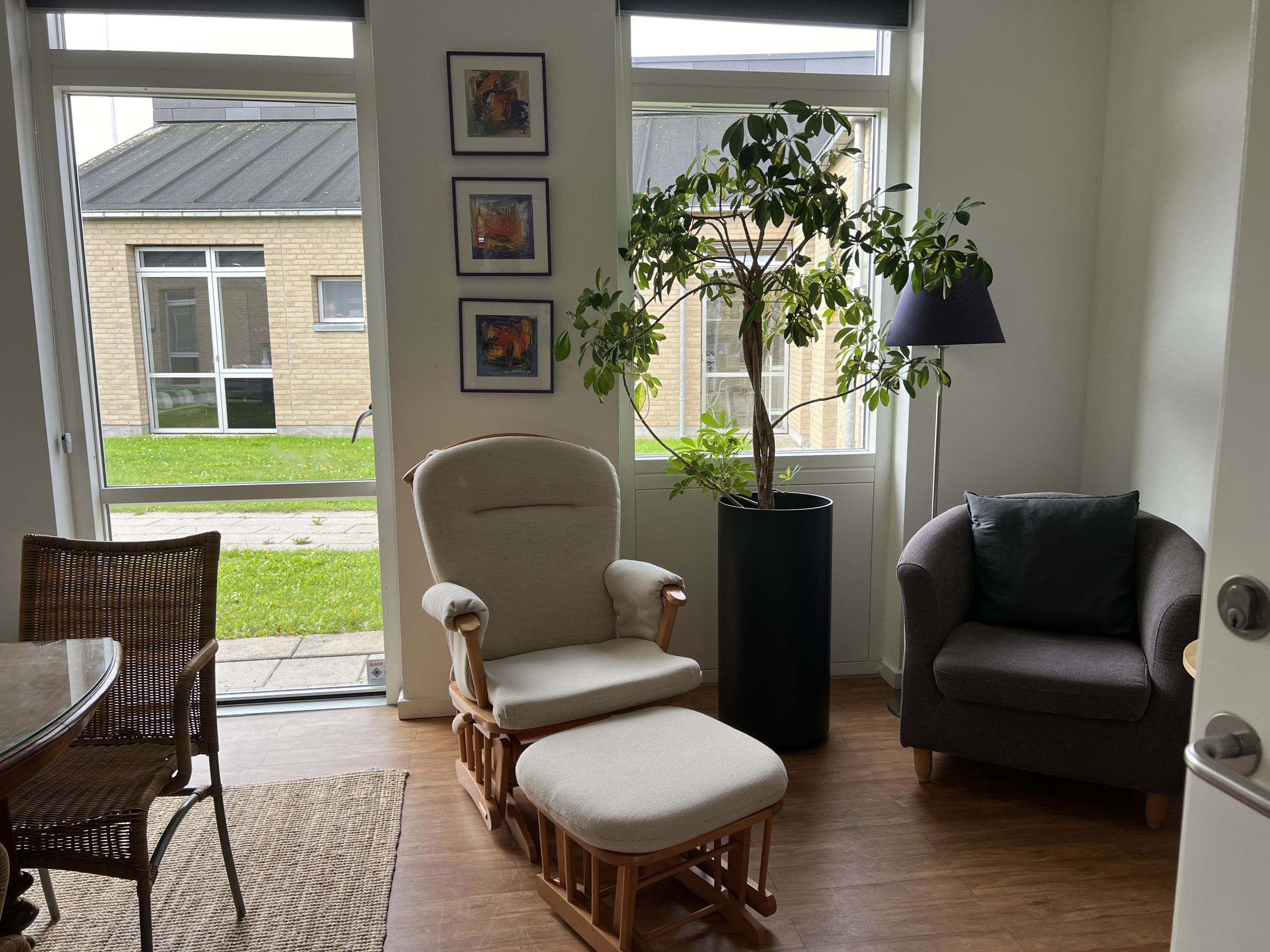 Familiehuset Bisgård Stue med lænestole, grønne planter og billeder