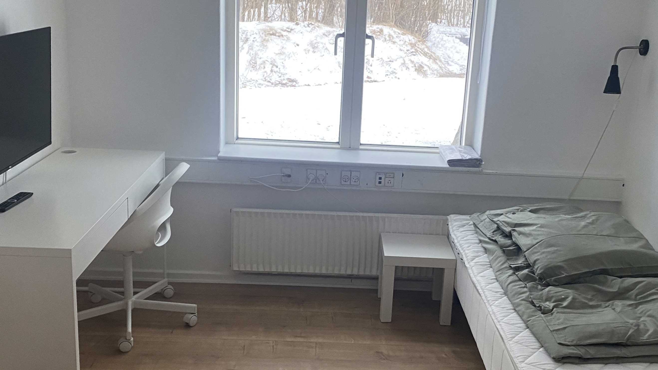 Værelse med seng, skrivebord, stol og computerskærm