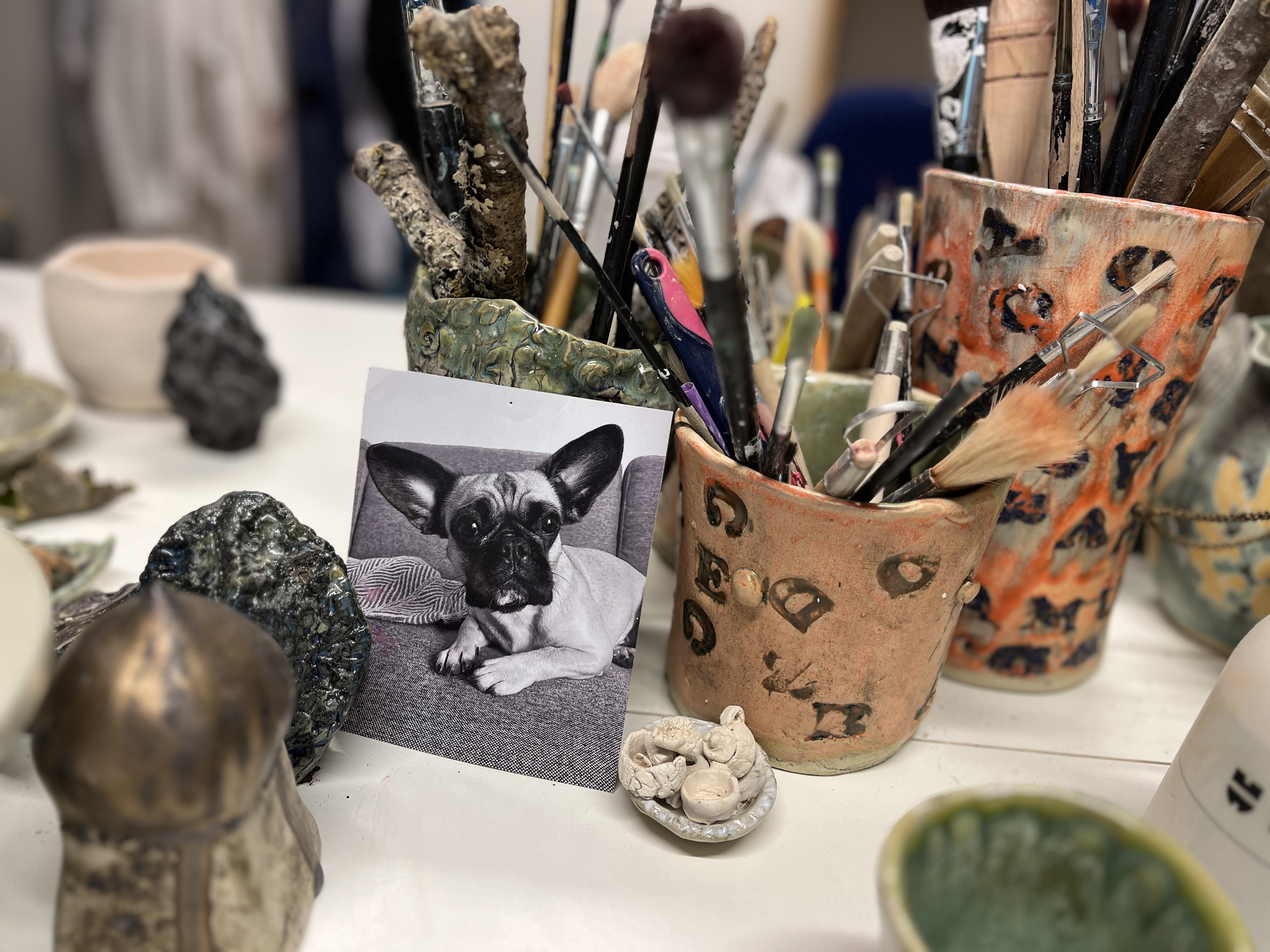 Skrivebord med pensler og et billede af en hund