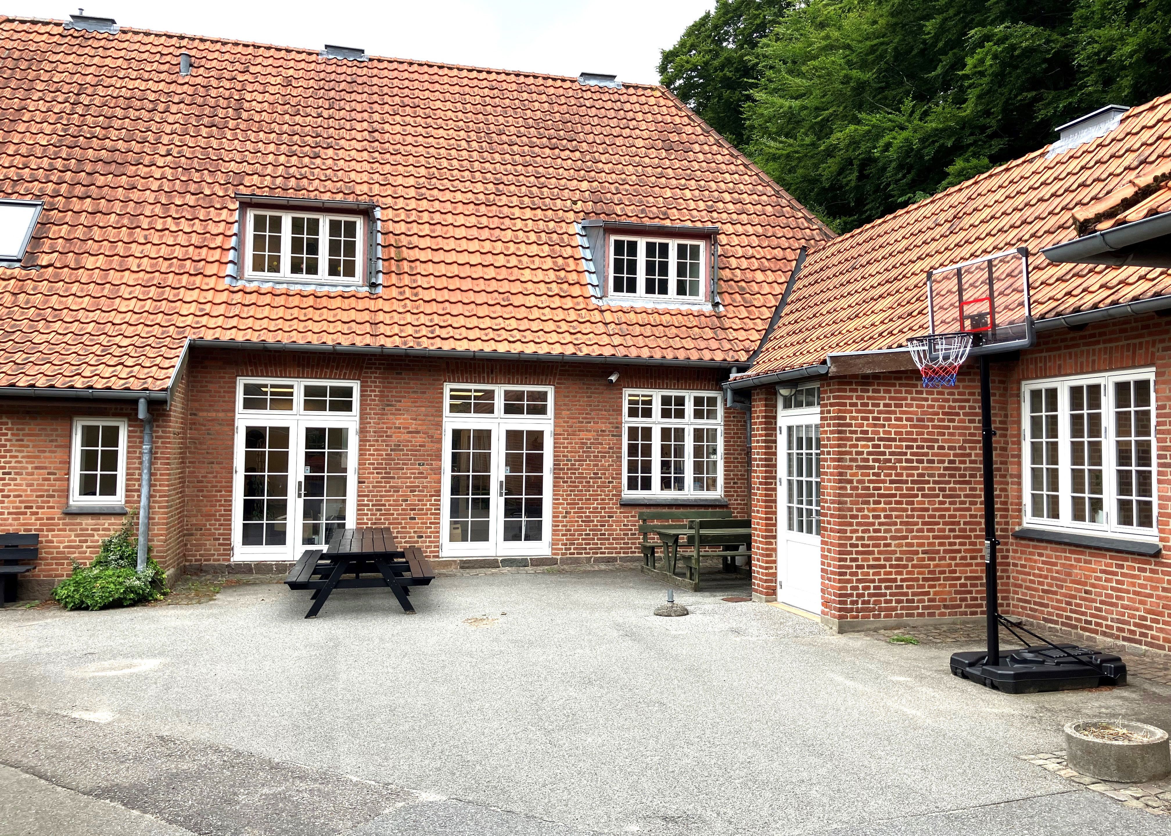 Rød bygning med en basketballkurv stående ved siden af