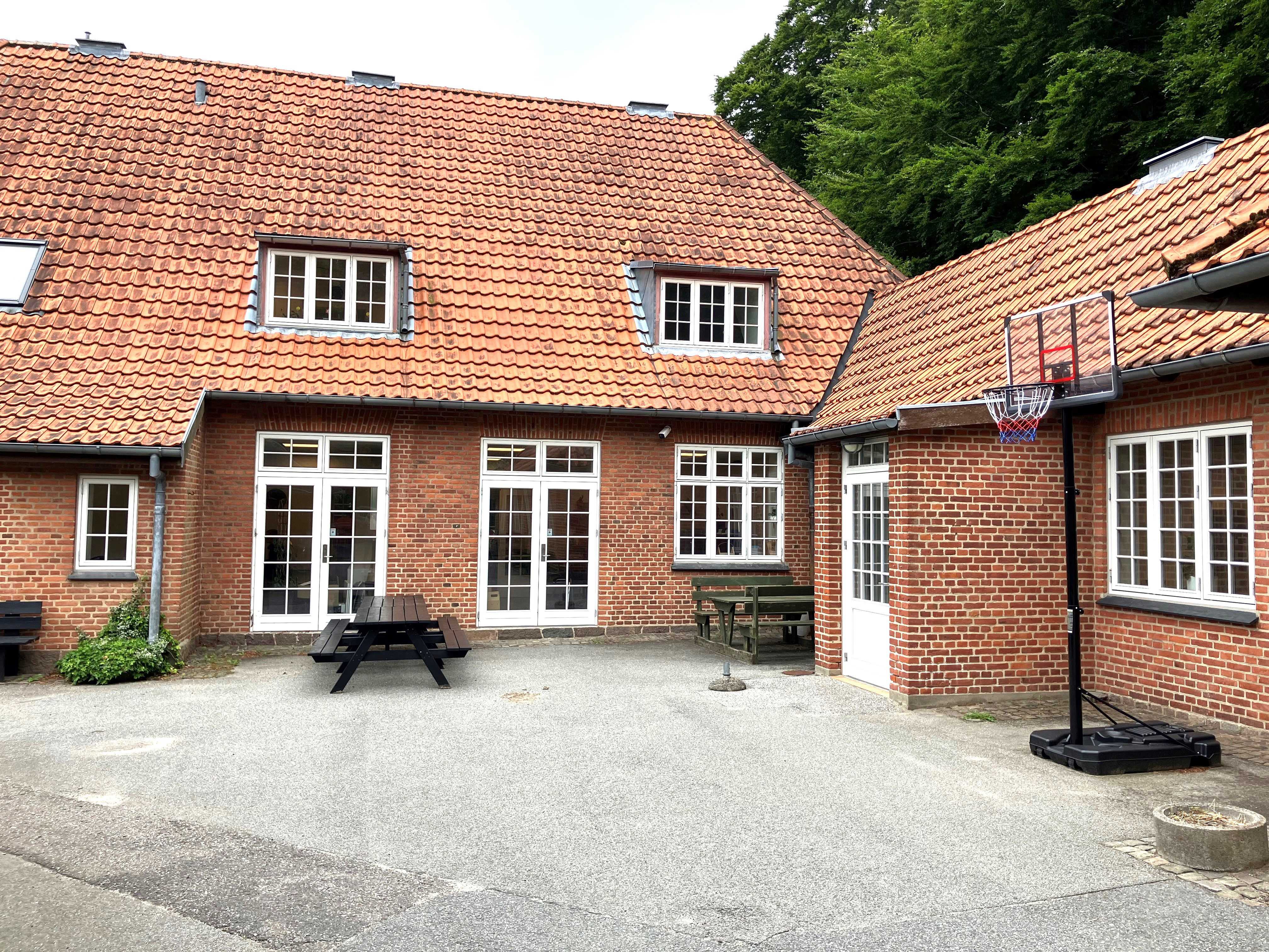 Rød bygning med en basketballkurv stående ved siden af