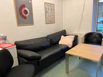 Stue med sort sofa, lænestol og sofabord