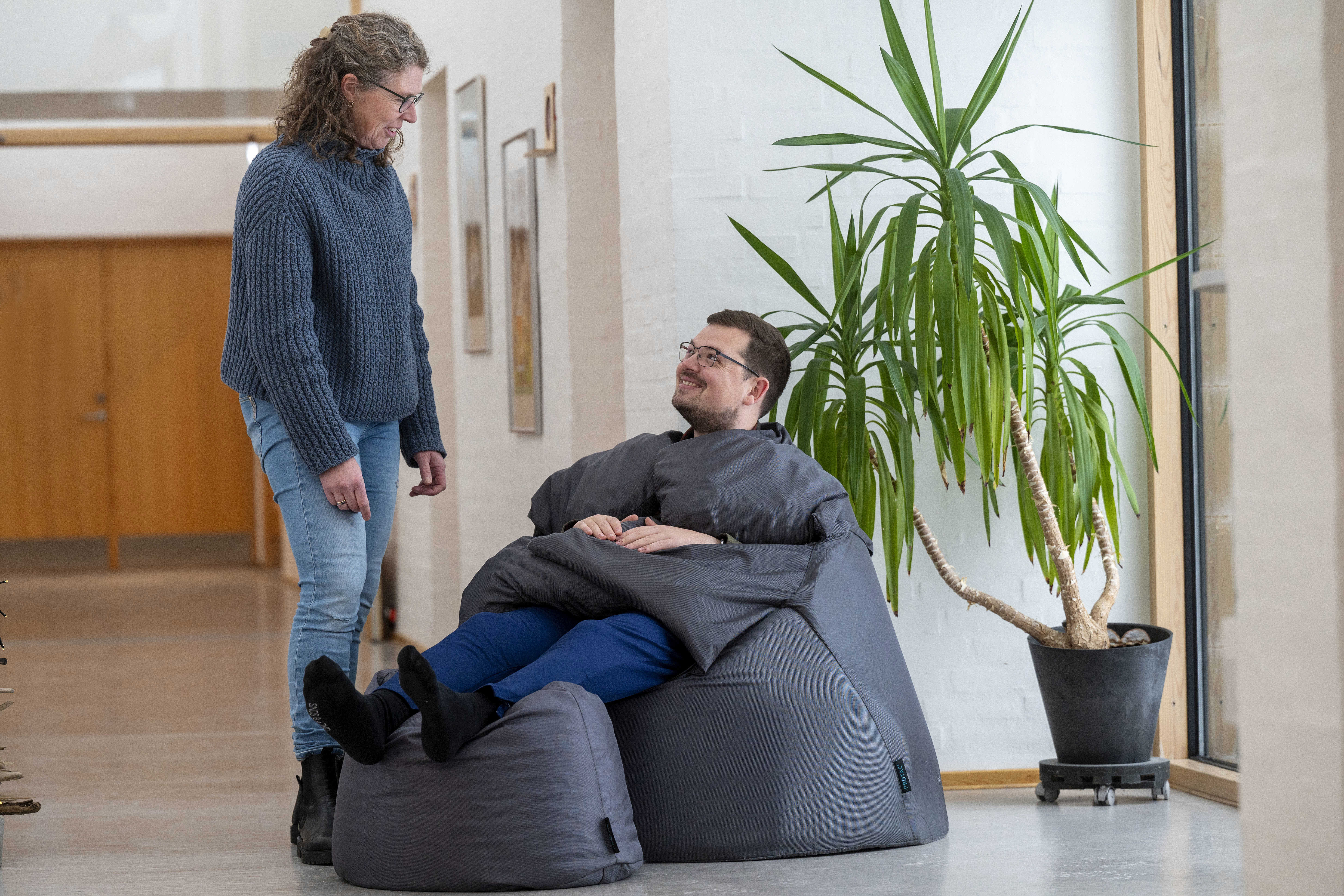 En borger i en sækkestol og en fagperson kigger på ham