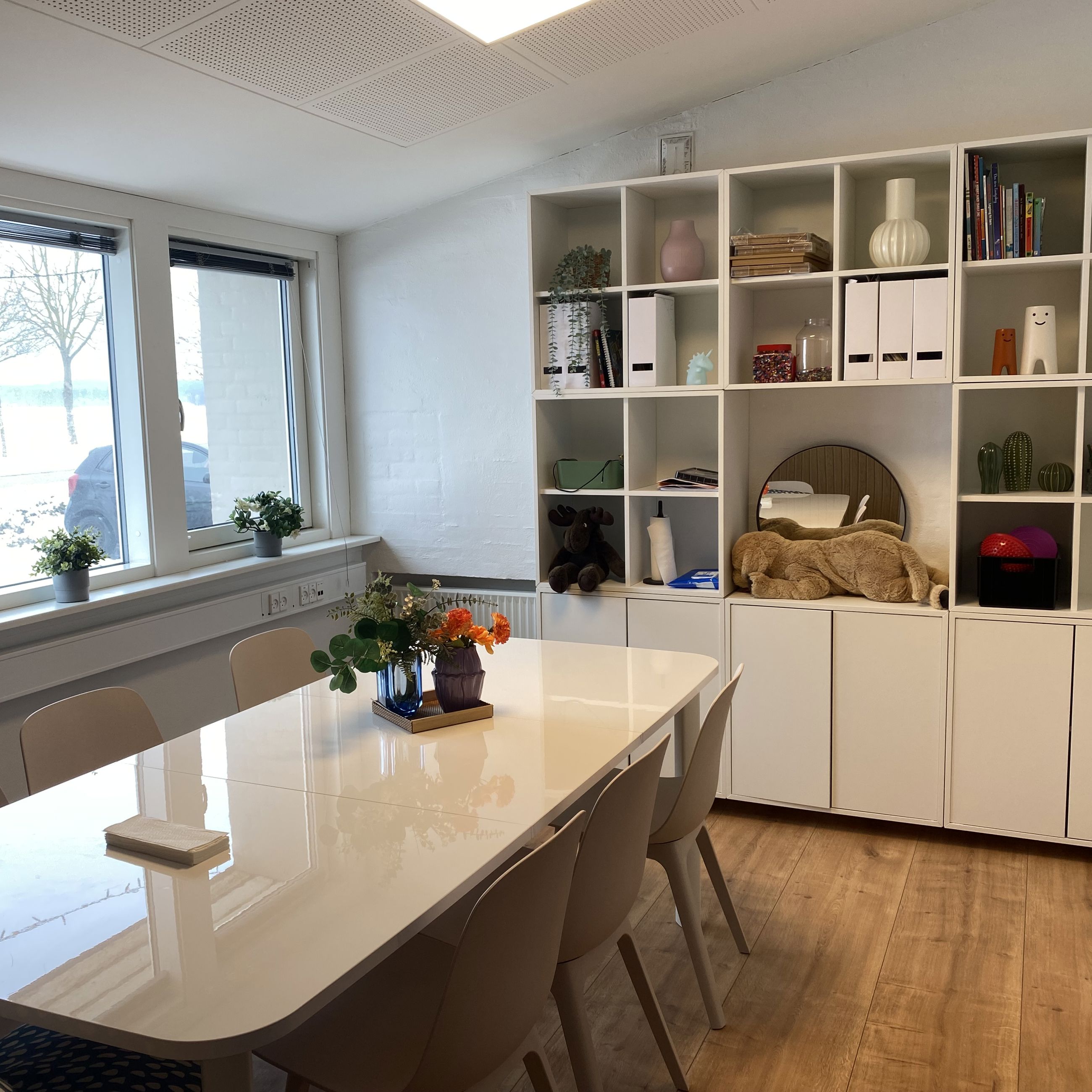 Mødelokale med mødebord og reol med pynteting