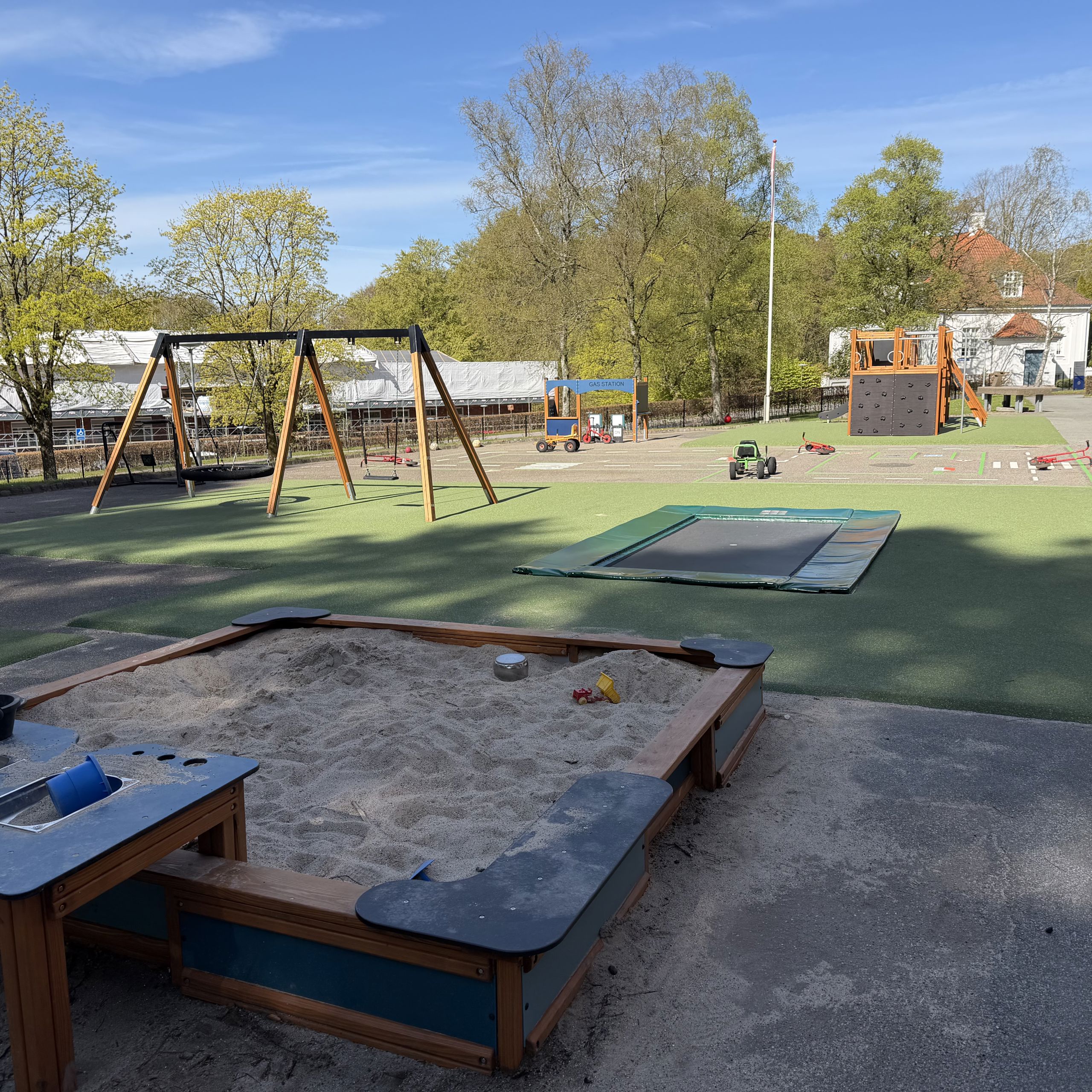 Legeplads med sandkasse, gynger og nedgravet trampolin, Nøddehuset
